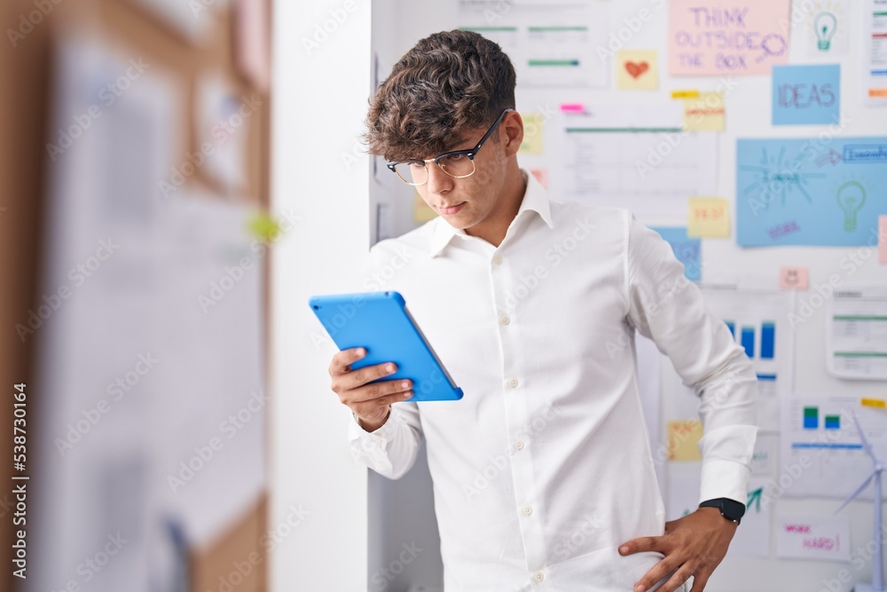 Young hispanic teenager business worker using touchpad at office