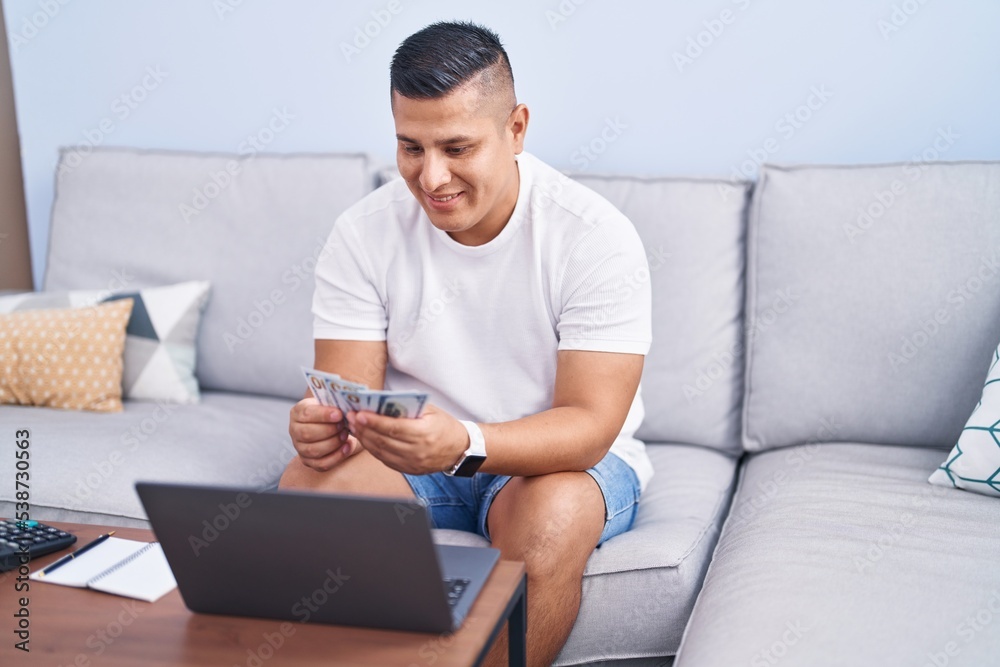 Young latin man using laptop accounting at home Young latin man using laptop accounting at home