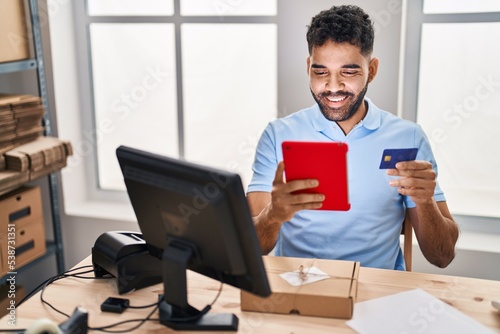 Young hispanic man ecommerce business worker using touchpad and credit card at office