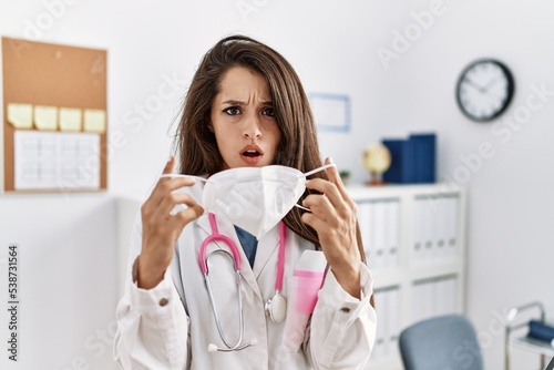 Young doctor woman wearing safety mask at the clinic angry and mad screaming frustrated and furious  shouting with anger. rage and aggressive concept.