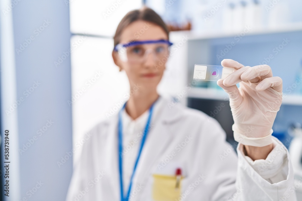 Young caucasian woman scientist holding sample at laboratory