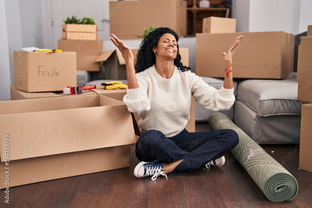 African american woman sitting on floor with winner expression at new home