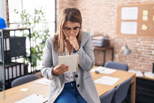 Young hispanic woman working at the office wearing glasses feeling unwell and coughing as symptom for cold or bronchitis. health care concept.