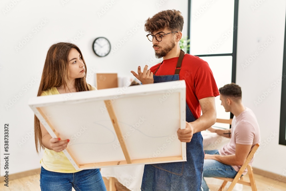 Group of people drawing sitting on the table. Man and woman concentrated looking to canvas at art studio.