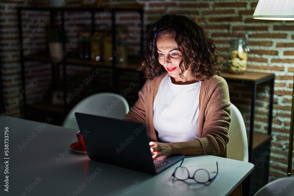 Middle age hispanic woman using laptop at night at home Middle age hispanic woman using laptop at night at home