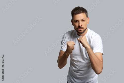 Man ready to fight on grey background, space for text