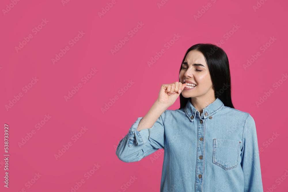 Young woman biting her nails on pink background. Space for text Young woman biting her nails on pink background. Space for text