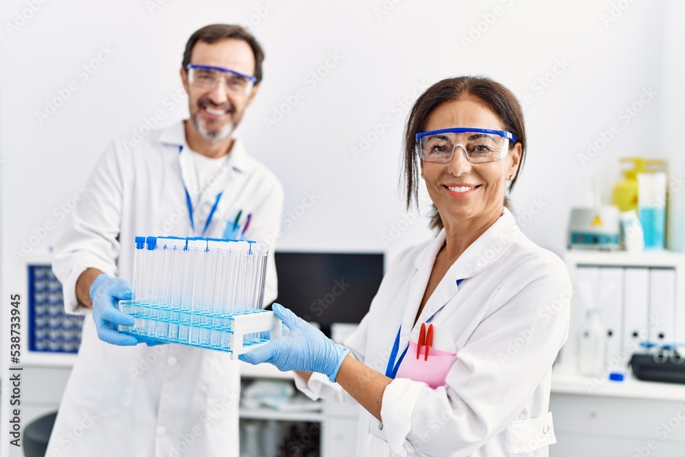 Middle age man and woman partners wearing scientist uniform holding test tube at laboratory Middle age man and woman partners wearing scientist uniform holding test tube at laboratory
