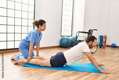 Middle age man and woman concentrate having rehab session stretching at physiotherapy clinic