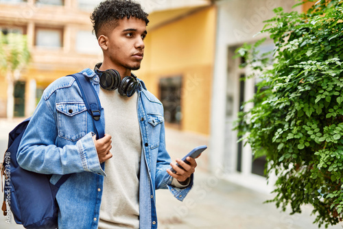 Hispanic young man using smartphone at the street