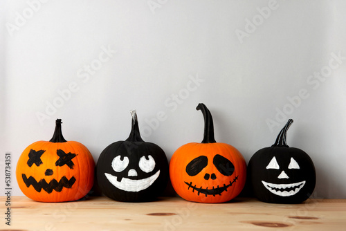 Halloween celebration. Pumpkins with spooky drawn faces on wooden table, space for text