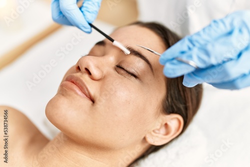 Young latin woman relaxed having eyebrows treatment at beauty center