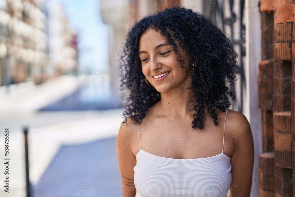 Young hispanic woman smiling confident looking to the side at street