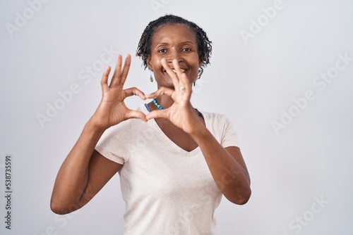 African woman with dreadlocks standing over white background smiling in love doing heart symbol shape with hands. romantic concept.