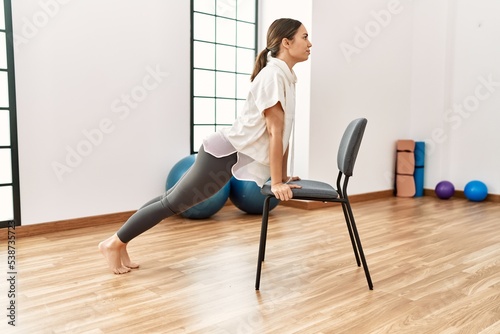 Young hispanic woman stretching at sport center.