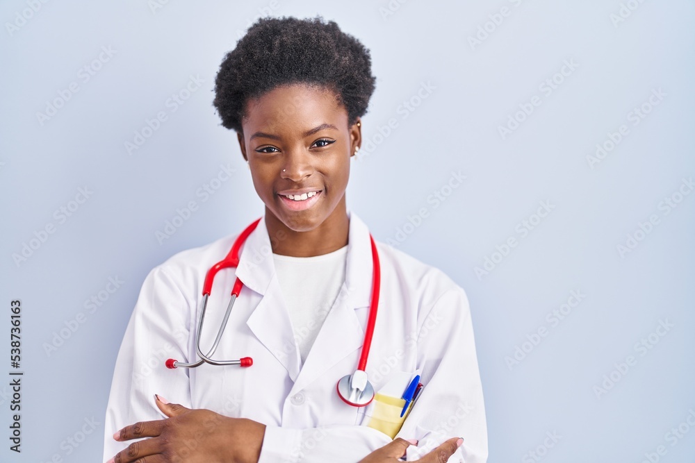 African american woman wearing doctor uniform and stethoscope happy face smiling with crossed arms looking at the camera. positive person. African american woman wearing doctor uniform and stethoscope happy face smiling with crossed arms looking at the camera. positive person.