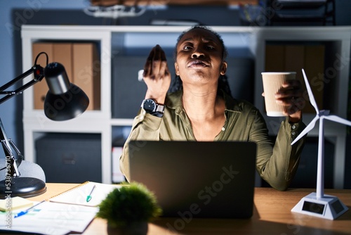 African woman working using computer laptop at night doing italian gesture with hand and fingers confident expression
