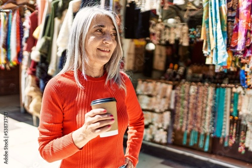 Middle age grey-haired woman smiling happy drinking coffee at the city.