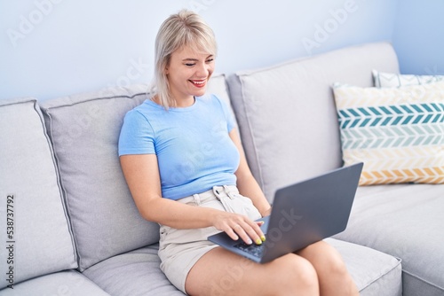 Young blonde woman using laptop sitting on table at home © Krakenimages.com