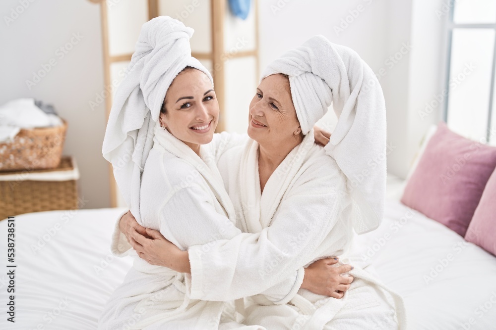 Mother and daughter wearing bathrobe hugging each other at bedroom Mother and daughter wearing bathrobe hugging each other at bedroom