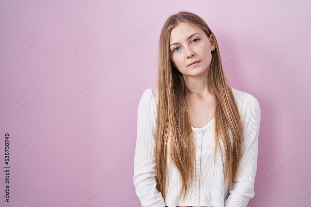 Young caucasian woman standing over pink background looking sleepy and tired, exhausted for fatigue and hangover, lazy eyes in the morning.