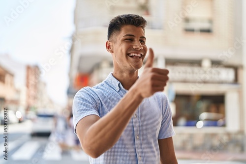 Young hispanic man smiling confident doing ok sign with thumb up at street