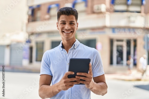 Young hispanic man smiling confident using touchpad at street © Krakenimages.com