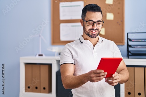 Young hispanic man business worker using touchpad at office