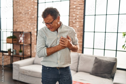 Middle age man touching chest suffering heart attack at home