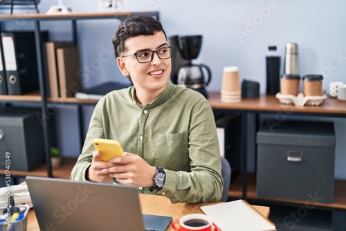 Young non binary man business worker using laptop and smartphone at office photo