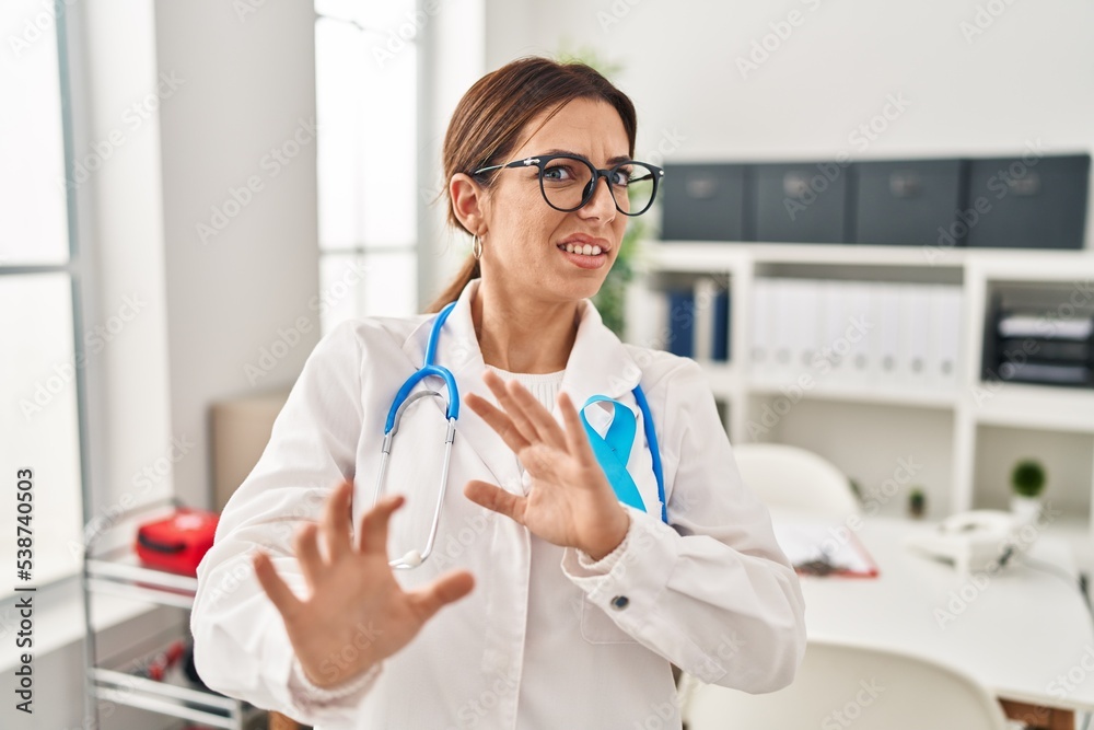 Young brunette doctor woman wearing stethoscope at the clinic disgusted expression, displeased and fearful doing disgust face because aversion reaction. with hands raised Young brunette doctor woman wearing stethoscope at the clinic disgusted expression, displeased and fearful doing disgust face because aversion reaction. with hands raised