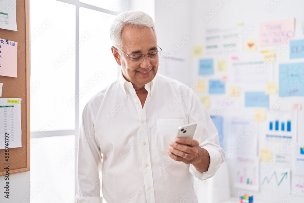 Middle age grey-haired man business worker smiling confident using smartphone at office