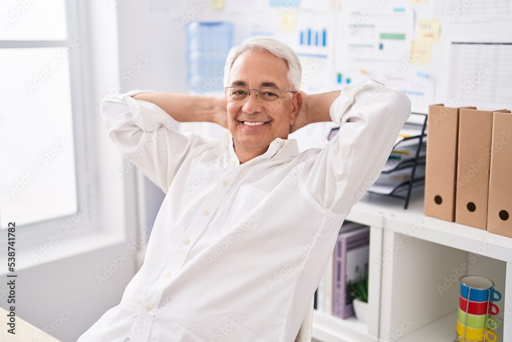 Middle age grey-haired man business worker relaxed with hands on head at office Middle age grey-haired man business worker relaxed with hands on head at office