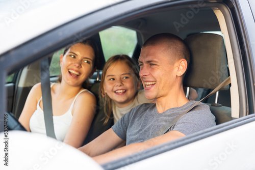 Portrait of happy family of three in a car salon