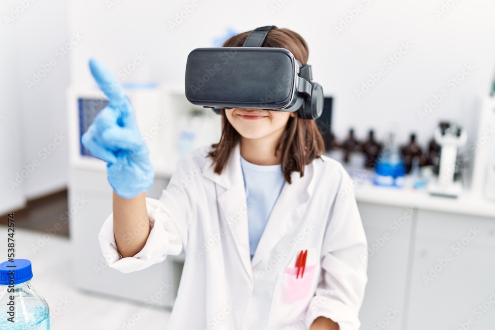 Naklejka premium Young hispanic girl wearing virtual reality glasses at laboratory