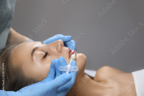 Beautiful woman getting lips injection in salon