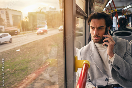 Young business man talking on a phone while commuting on a bus