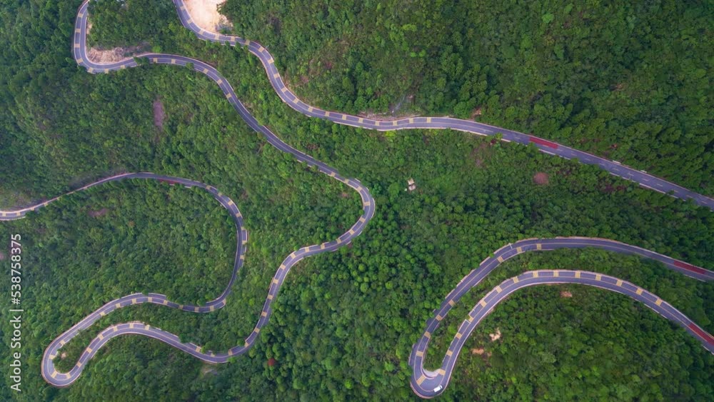 A winding road between green trees and mountains A winding road between green trees and mountains