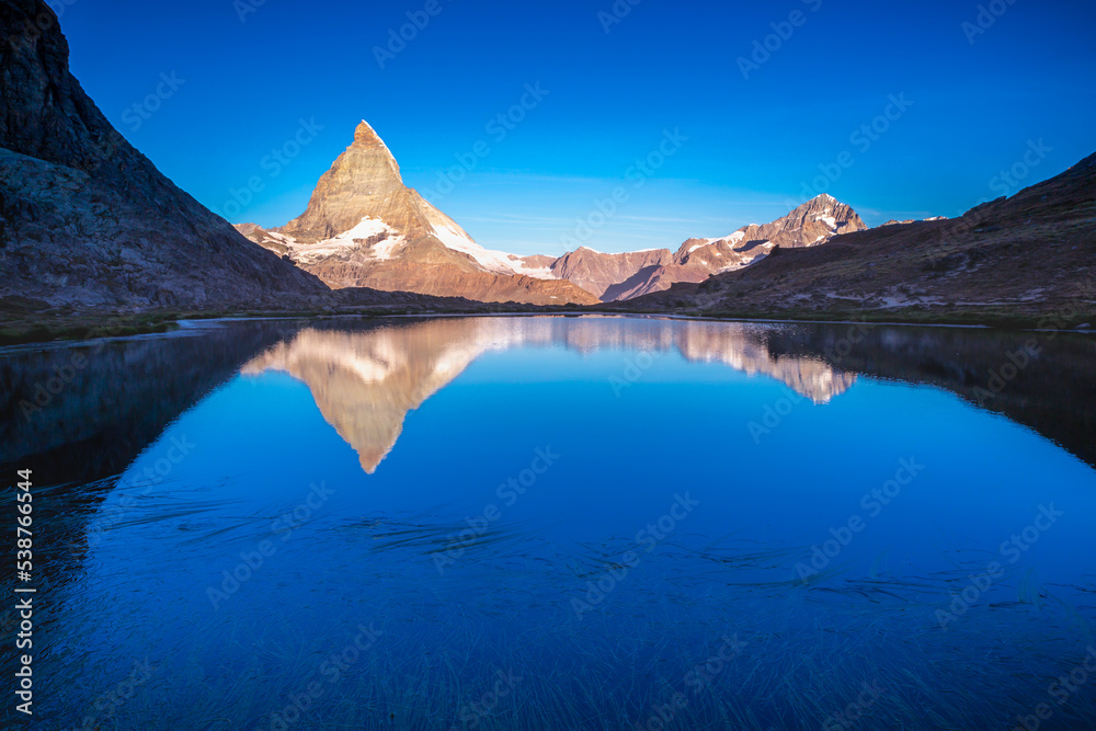 Matterhorn iconic mountain and lake relfection at peaceful sunrise, Swiss Alps