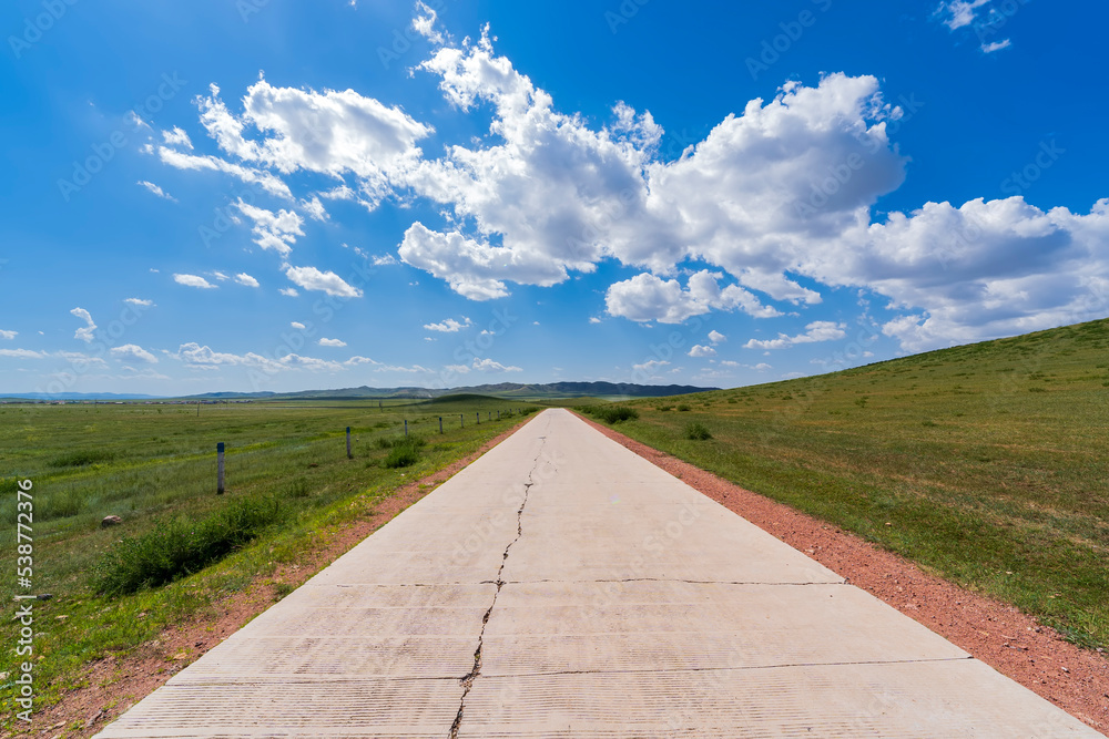 The tarmac road is under blue sky and white clouds