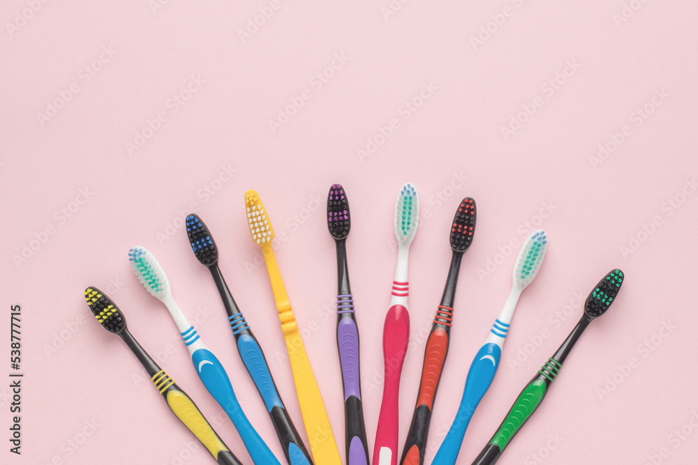 Obraz premium Plastic toothbrushes on a light pink background. Flat lay.