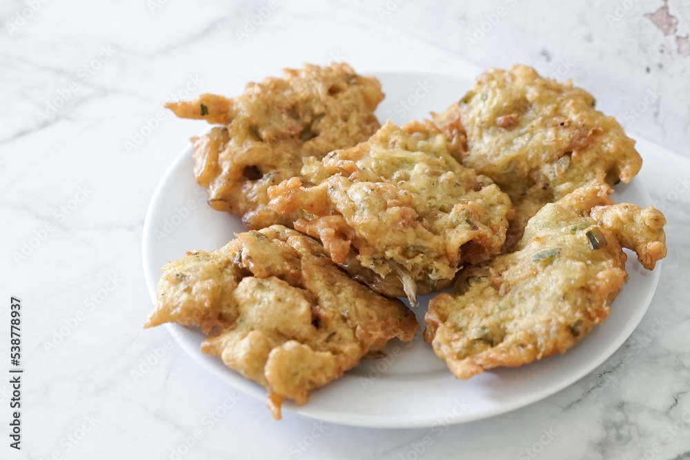 Bakwan goreng, fried food, Indonesian traditional street food snacks. fried vegetables dough fritters, appetizer on a white plate Bakwan goreng, fried food, Indonesian traditional street food snacks. fried vegetables dough fritters, appetizer on a white plate