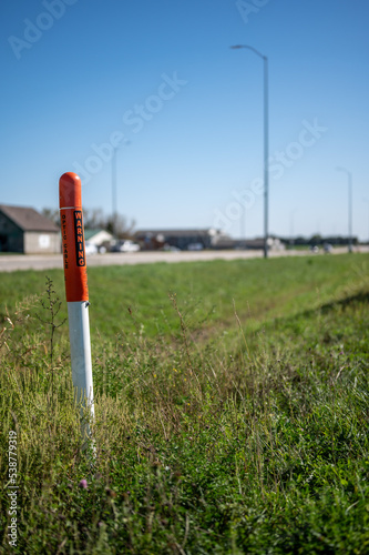 Marker post for underground internet optics line along a road ditch. 