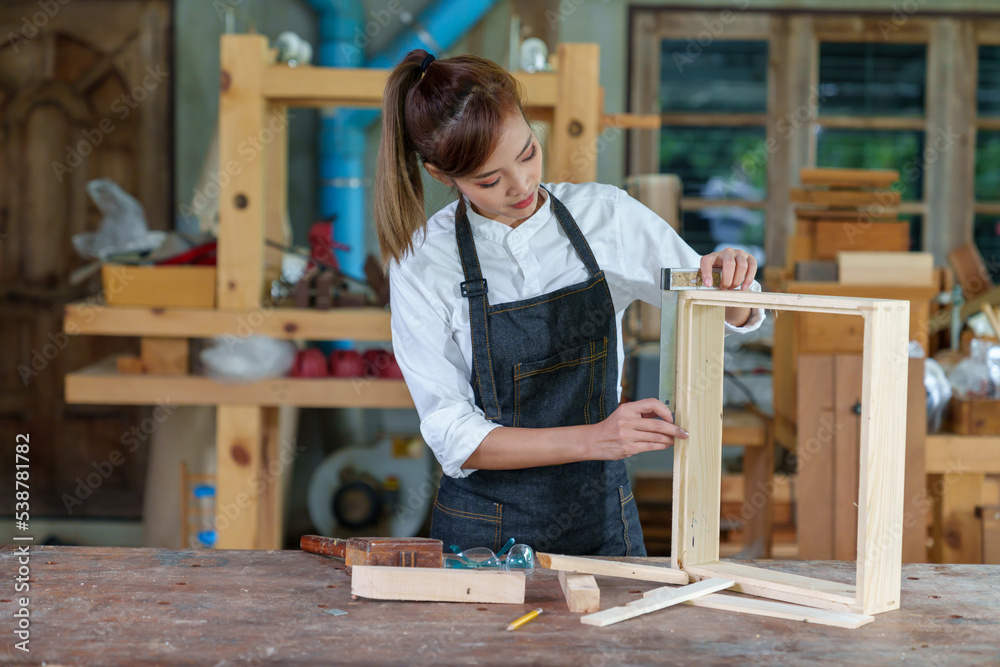 portrait of beautiful asian woman carpenter dealing with handicraft, woman has own business connected with making wooden furniture in workshop portrait of beautiful asian woman carpenter dealing with handicraft, woman has own business connected with making wooden furniture in workshop