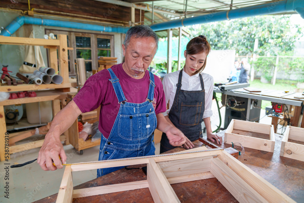 Tutor With Female Carpentry Student In Workshop Studying For Apprenticeship At College ,Teacher explaining a structure students while standing in a woodwork class