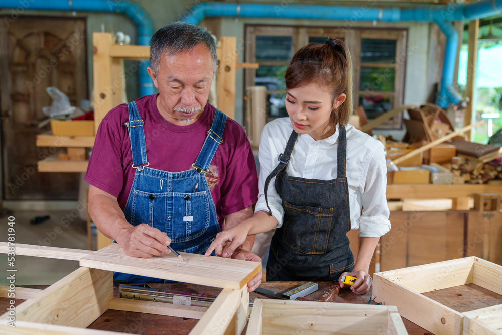 Tutor With Female Carpentry Student In Workshop Studying For Apprenticeship At College ,Teacher explaining a structure students while standing in a woodwork class