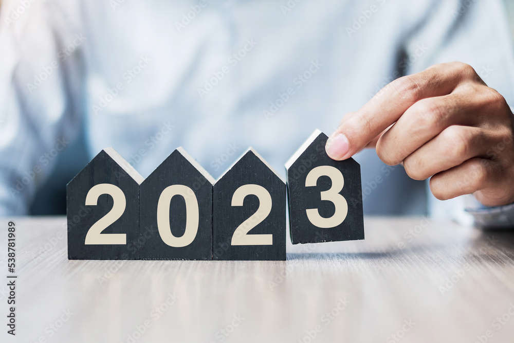 Businessman hands holding 2023 Happy New Year with house model on table office. New House, Financial, Property insurance, real estate, savings and New Year Resolution concepts Businessman hands holding 2023 Happy New Year with house model on table office. New House, Financial, Property insurance, real estate, savings and New Year Resolution concepts