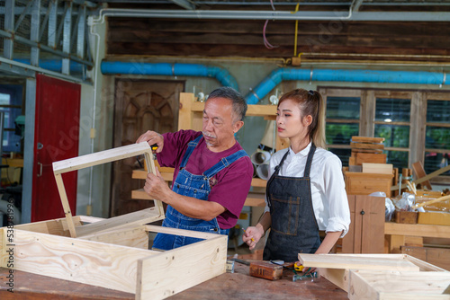 Tutor With Female Carpentry Student In Workshop Studying For Apprenticeship At College ,Teacher explaining a structure students while standing in a woodwork class