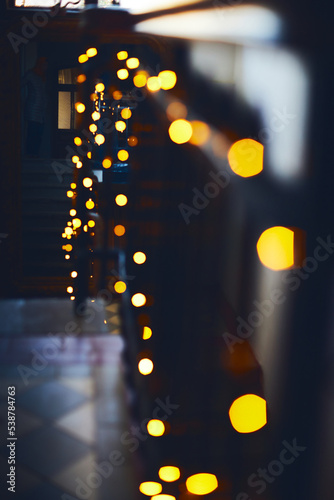 The staircase in the building at Christmas in a glowing garland goes up to the mirror. Blurred background. Vertical photo.