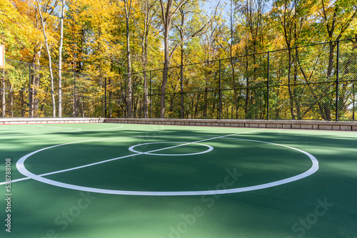 Interesting green and red outdoor basketball court at school playground.  Court includes retaining walls and black vinyl coated chain link fence.  © Thomas